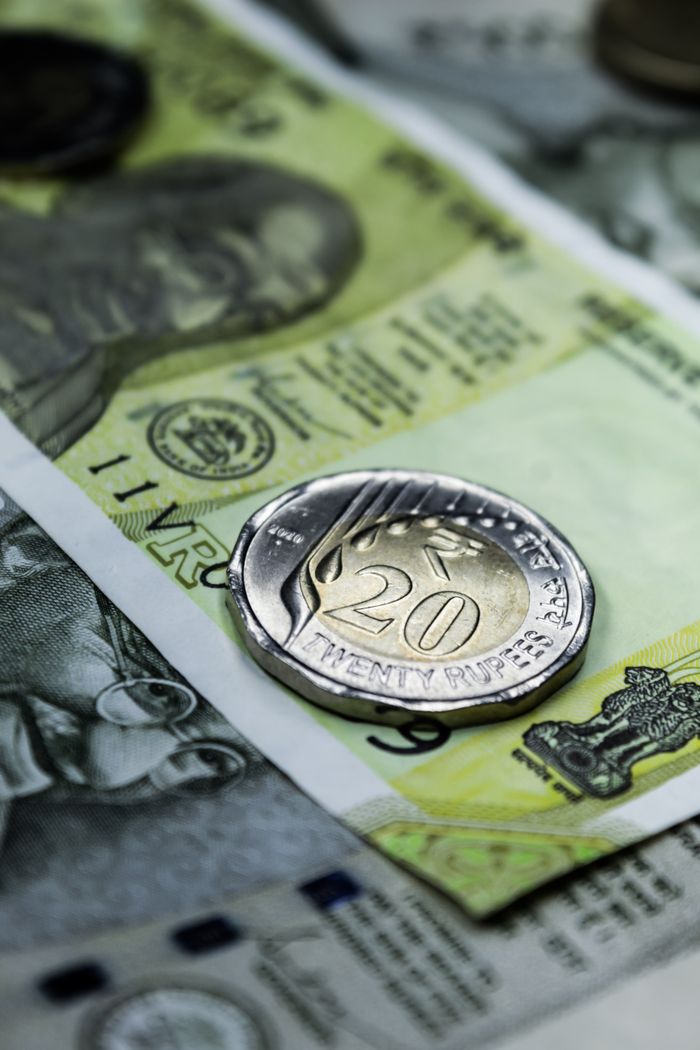Close-up photo of a 20 rupee coin on Indian currency notes, showcasing Indias financial themes.